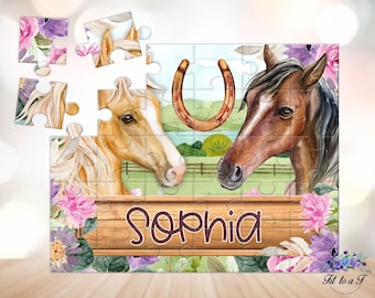 May include: A jigsaw puzzle featuring a watercolor illustration of a light brown horse and a dark brown horse facing each other, with a horseshoe above them. A wooden plank with the name Sophia printed in dark brown text sits below the horses.