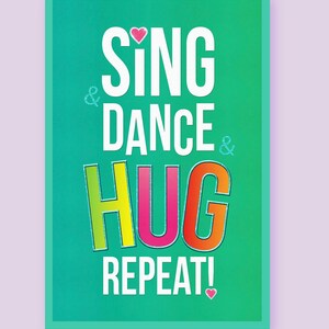 May include: A teal green card with the text "Sing & Dance & Hug Repeat!" in white, pink, yellow, orange, and red. There are small pink hearts at the top and bottom of the card.