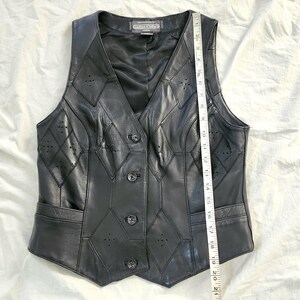 Puede incluir: Chaleco de cuero negro con cuello en V, dise&ntilde;o de patchwork en forma de diamante y cierre de botones. El chaleco tiene dos bolsillos delanteros y mide aproximadamente 53 cm de largo.