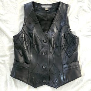 Puede incluir: Chaleco de cuero negro con cuello en V y cierre de botones. El chaleco presenta un patr&oacute;n de diamantes con peque&ntilde;os detalles perforados y dos bolsillos delanteros. Una prenda de vestir exterior cl&aacute;sica.
