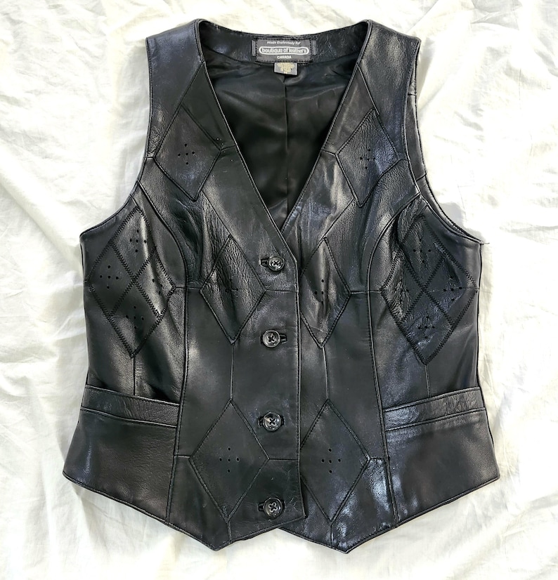 Puede incluir: Chaleco de cuero negro con cuello en V y cierre de botones. El chaleco presenta un patr&oacute;n de diamantes con peque&ntilde;os detalles perforados y dos bolsillos delanteros. Una prenda de vestir exterior cl&aacute;sica.