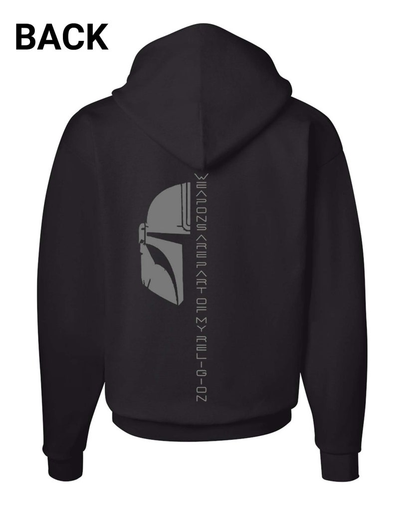 Puede incluir: Sudadera con capucha negra con un gr&aacute;fico de casco de Mandaloriano gris y el texto "This is the way" en escritura mandaloriana en la parte posterior.