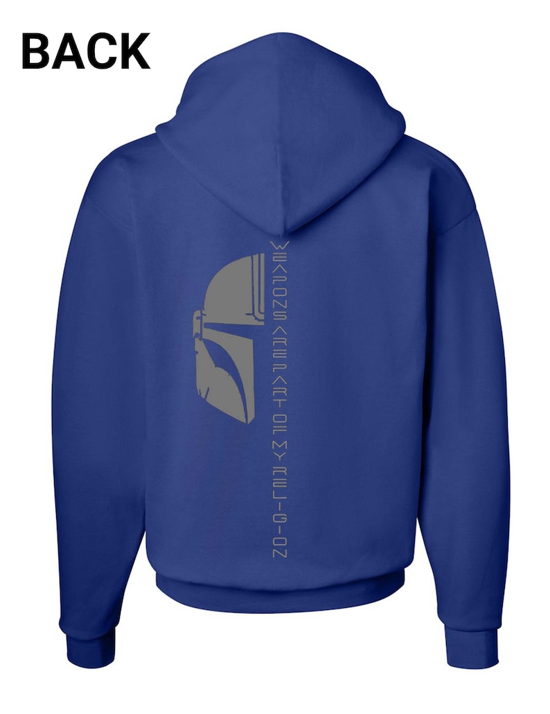 Puede incluir: Una sudadera con capucha azul real con un gr&aacute;fico de casco mandaloriano gris y el texto "This is the way" en una fuente vertical invertida en la parte posterior.