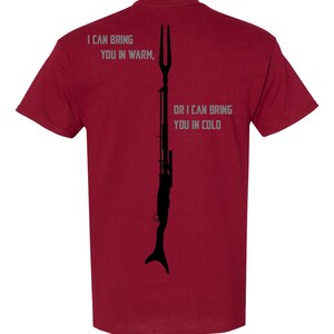 May include: Burgundy t-shirt with a black silhouette of a weapon and the text "I can bring you in warm, or I can bring you in cold".