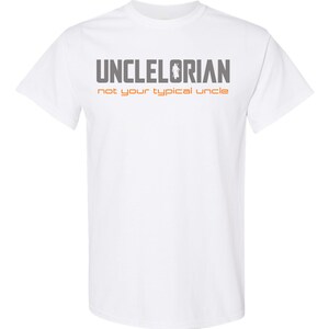 Puede incluir: Camiseta blanca con el texto "UNCLELORIAN not your typical uncle" en gris y naranja.