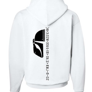 Puede incluir: Sudadera con capucha blanca con una silueta negra de un casco mandaloriano y el texto "Weapons are part of my religion" impreso en la espalda.