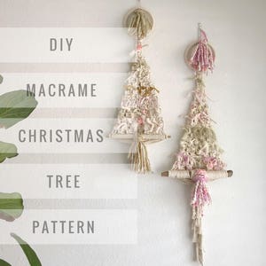May include: Two macrame Christmas tree wall hangings. One is cream with gold accents and the other is cream with pink accents. Both have a wooden dowel at the bottom.