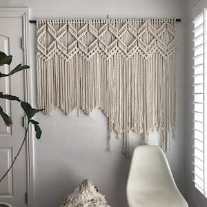 Peut inclure: Une grande tapisserie murale en macram&eacute; blanche avec un motif g&eacute;om&eacute;trique. La tapisserie est faite de cordon de coton &eacute;pais et a une frange en bas.