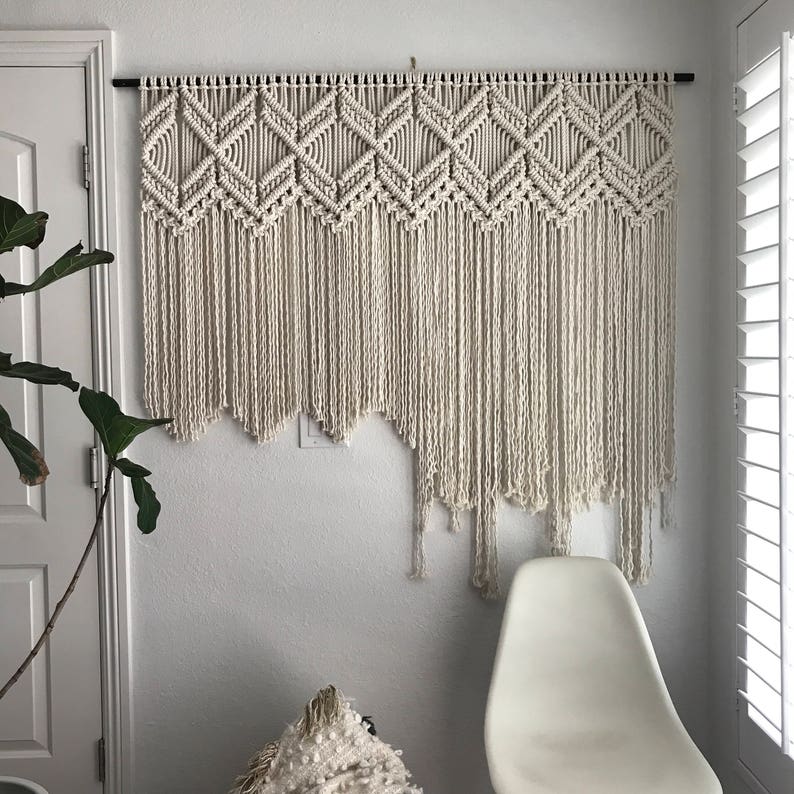 Peut inclure: Une grande tapisserie murale en macram&eacute; blanche avec un motif g&eacute;om&eacute;trique. La tapisserie est faite de cordon de coton &eacute;pais et a une frange en bas.
