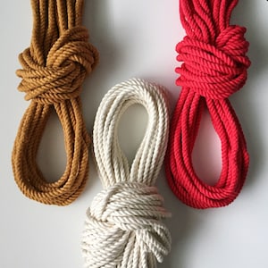 May include: Three spools of rope in different colors: brown, white, and red. The rope is thick and twisted.