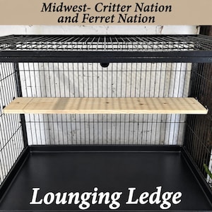 May include: A rectangular light-colored wooden lounging ledge installed inside a black metal wire cage. The text Midwest- Critter Nation and Ferret Nation and Lounging Ledge is visible in the image. The cage features a black metal base tray.