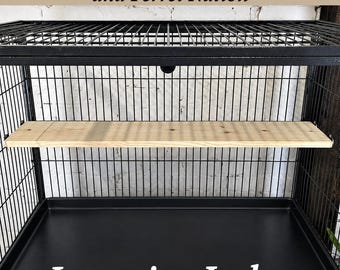 May include: A rectangular light-colored wooden lounging ledge installed inside a black metal wire cage. The text Midwest- Critter Nation and Ferret Nation and Lounging Ledge is visible in the image. The cage features a black metal base tray.