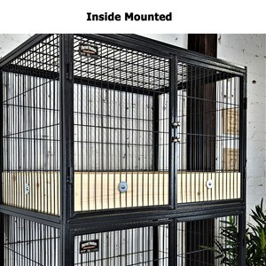 May include: Black metal pet cage with wire mesh sides and doors. The cage has a wooden base and the text "Inside Mounted" at the top. The cage is designed for indoor use.