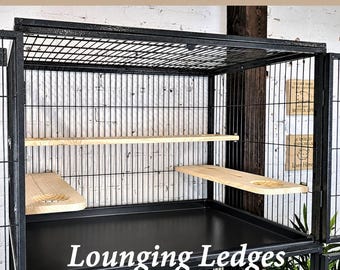 May include: A black metal animal cage featuring light-colored wooden lounging ledges installed inside. The cage has a wire grid structure with a solid black base tray. Text at the top reads Midwest Critter Nation & Ferret Nation.