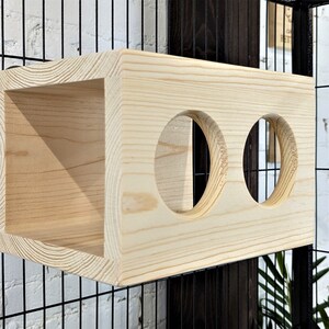 May include: A wooden cat toy with two round holes. The toy is made of natural wood and has a light brown color.