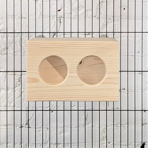 May include: A wooden feeder with two round openings for small animals. The feeder is made of natural wood and is designed to be hung inside a cage.