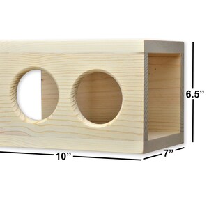 May include: A natural wood cat toy with two round holes. The toy measures 10 inches wide, 7 inches deep, and 6.5 inches tall.