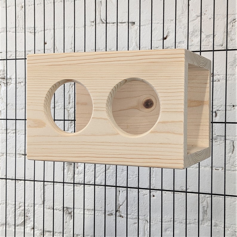 May include: A wooden box with two circular openings, designed for small animals to play and explore. The box is made of natural wood and has a light brown color.