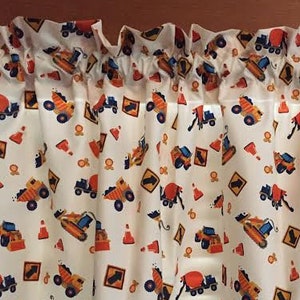 May include: White valance with a repeating pattern of construction vehicles, including dump trucks, cement mixers, and bulldozers. The vehicles are orange, yellow, and blue, and the background is white with orange and yellow accents.