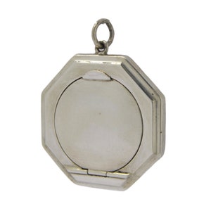 May include: A silver octagonal locket with a hinged lid. The locket has a smooth, polished surface and a simple design.