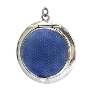 May include: A silver locket with a circular, hinged design. The locket has a textured, royal blue centre. A small loop is at the top for a chain. The locket is designed to hold a photograph or small keepsake. The locket measures approximately 3 cm in diameter.