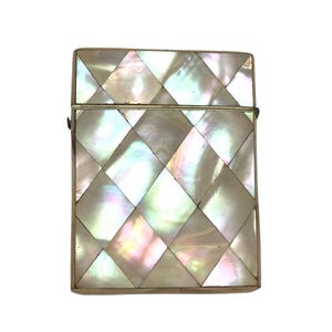 May include: A rectangular, iridescent mother-of-pearl box with a silver-colored metal frame. The box is covered in a diamond pattern of shimmering, opalescent tiles. The hinged lid is closed. The box is likely vintage or antique.