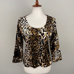 May include: A brown and white leopard print top with a scoop neck and 3/4 sleeves.