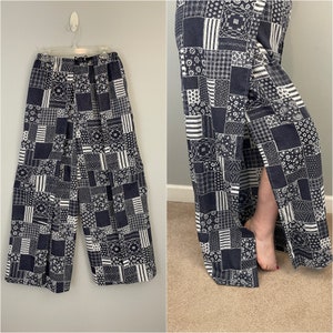 May include: Black and white patchwork wide-leg pants with a side slit. The pants have a drawstring waist and a relaxed fit.