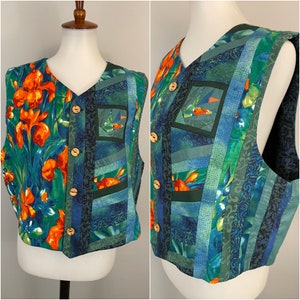 May include: A vibrant V-neck vest with a floral and patchwork design. The vest features orange irises, blue and green fabrics, wooden buttons, and a square pocket with a sailboat motif. The garment is a striking piece.