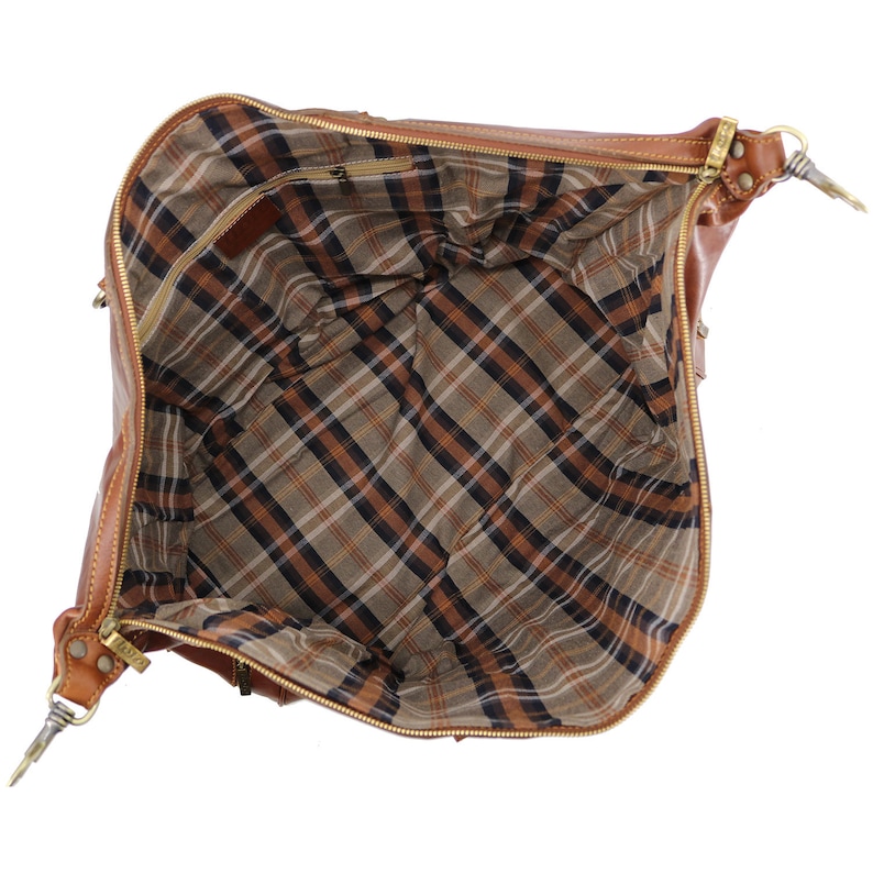 May include: Open brown leather handbag with a plaid interior. The bag has a zipper closure and gold-colored hardware. The interior features a brown, black, and tan plaid pattern. The bag is empty and open, showing the interior lining.