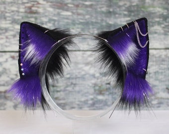 May include: Purple and black cat ears headband with a silver chain detail. The headband is on a white surface.