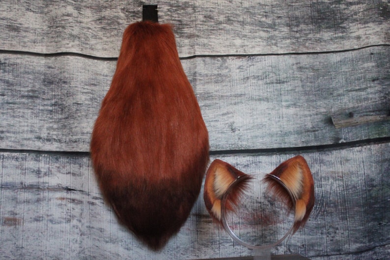 May include: A set of fox costume accessories, including a fluffy brown tail and a headband with two brown fur ears.
