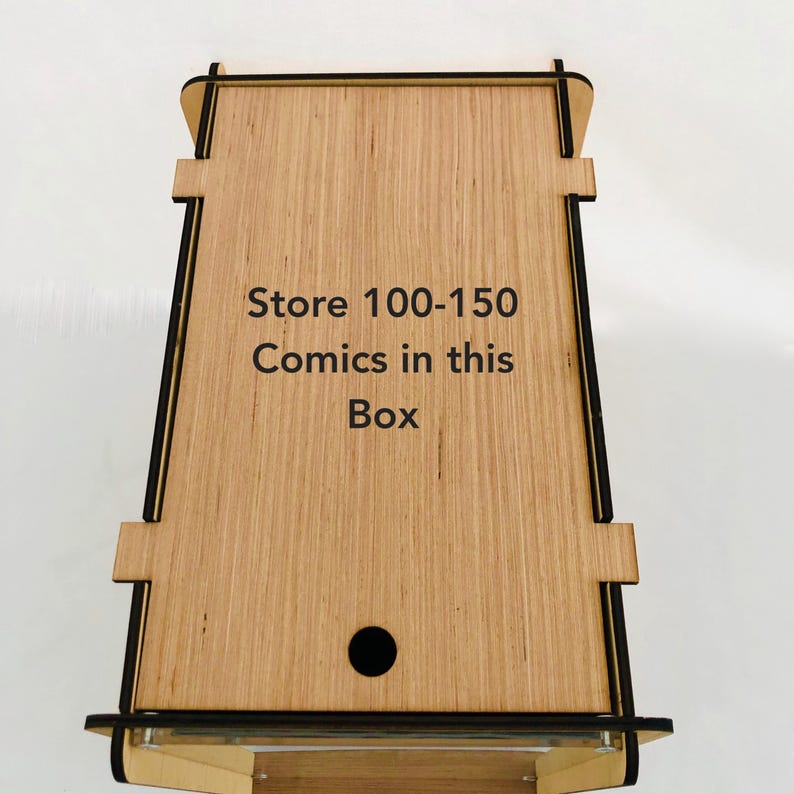 Pu&ograve; includere: Scatola di legno con bordo nero e un foro rotondo nella parte superiore. La scatola &egrave; etichettata "Store 100-150 Comics in this Box".