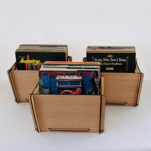 May include: Three wooden record storage crates with vinyl records inside. The crates are made of light brown wood and have a simple design. The records include "The Honey Drippers", "Crosby, Stills, Nash & Young", and "Cyndi Lauper".