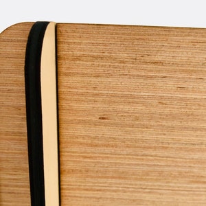 Pu&ograve; includere: Primo piano di una scatola di legno con un elastico nero. La scatola ha una venatura del legno marrone chiaro e una finitura naturale.