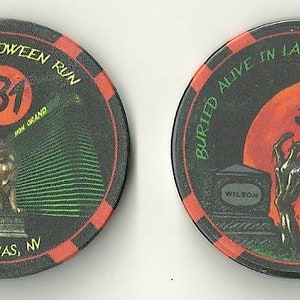 May include: Two black casino chips with Halloween-themed designs. One chip features the text "2018 Halloween Run" and "Las Vegas, NV", with a lion statue and the MGM Grand. The other chip has a zombie hand, a witch, and the text "Buried Alive in Las Vegas."