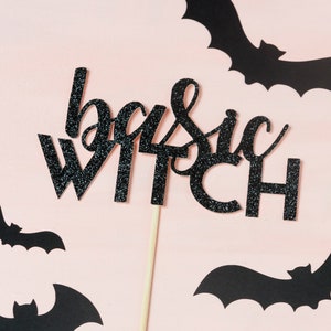 May include: Black glitter cake topper with the text "basic witch" on a pink background with black bat cutouts.