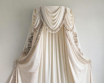 May include: A cream-coloured fabric canopy featuring draped swags and vertical panels. The edges are adorned with intricate beige tassel fringe trim, creating a layered effect that hangs from a central point against a plain wall.