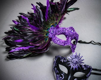 May include: A pair of masquerade masks with feathers. One mask is purple with rhinestones and the other is black with a silver sun design.