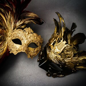 Puede incluir: Dos m&aacute;scaras doradas ornamentadas para carnaval con dise&ntilde;os intrincados y adornos de plumas. Una m&aacute;scara es principalmente dorada con plumas rojas y marrones, la otra es negra y dorada con un dise&ntilde;o cl&aacute;sico.
