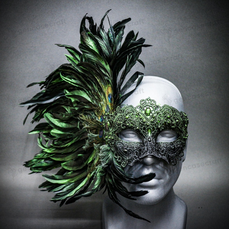 Peut inclure: Un masque de mascarade d&eacute;coratif avec une base noire et des d&eacute;tails en dentelle verte complexes. Le masque est orn&eacute; de plumes vertes vibrantes et d'une plume de paon. Le masque est pr&eacute;sent&eacute; sur une t&ecirc;te de mannequin blanche.