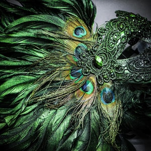 Peut inclure: Gros plan d'un masque de bal masqu&eacute; vert et noir avec des plumes de paon. Le masque pr&eacute;sente des d&eacute;tails en dentelle complexes, orn&eacute;s de pierres pr&eacute;cieuses vertes. Les plumes de paon ont des accents bleus, dor&eacute;s et verts vibrants.