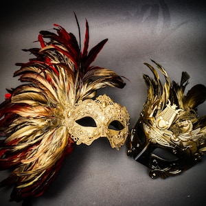 Puede incluir: Dos m&aacute;scaras de carnaval ornamentadas. Una es dorada con plumas rojas y doradas, la otra es negra y dorada con un dise&ntilde;o de lira y plumas doradas. Ambas m&aacute;scaras tienen detalles intrincados sobre un fondo gris.