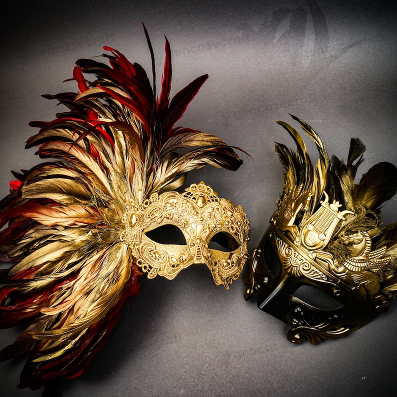 Puede incluir: Dos m&aacute;scaras de carnaval ornamentadas. Una es dorada con plumas rojas y doradas, la otra es negra y dorada con un dise&ntilde;o de lira y plumas doradas. Ambas m&aacute;scaras tienen detalles intrincados sobre un fondo gris.