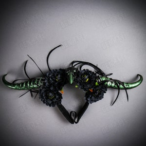 Puede incluir: Una diadema negra con cuernos verdes y flores negras. La diadema está decorada con plumas.