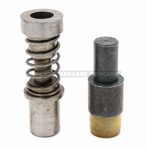May include: Two metal components, likely for a machine or tool. One has a spring and a cylindrical top with a hole. The other is a solid cylinder with a brass-colored base.