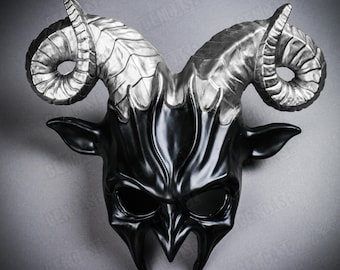 May include: A black and silver horned mask with a demonic design. The mask features large, curved horns with a silver finish, and a glossy black face with pointed features and eye openings. The mask is likely for costume or decorative purposes.