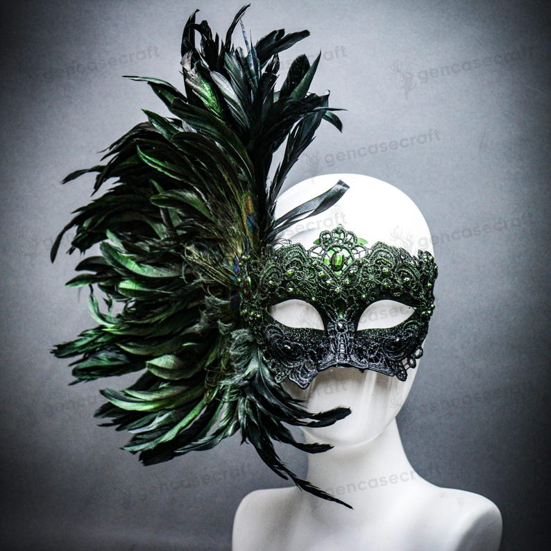 Peut inclure: Un masque de bal noir et vert avec une plume de plumes. Le masque pr&eacute;sente des d&eacute;tails de dentelle complexes et est orn&eacute; de pierres pr&eacute;cieuses vertes. Les plumes sont vert fonc&eacute; et noires.