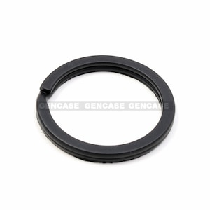 May include: A black rubber key ring with a smooth, rounded surface.