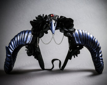 May include: A gothic-style headpiece featuring curved blue horns with black accents. The headpiece includes a black bird skull with a red gem, black roses, and silver chain details. The horns are approximately 10 inches long.